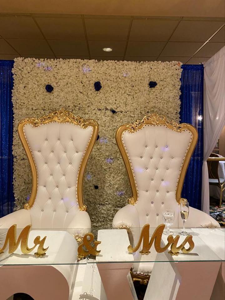 Wedding head table with white flower wall, blue rose accents, gold thrones, and Mr and Mrs signs